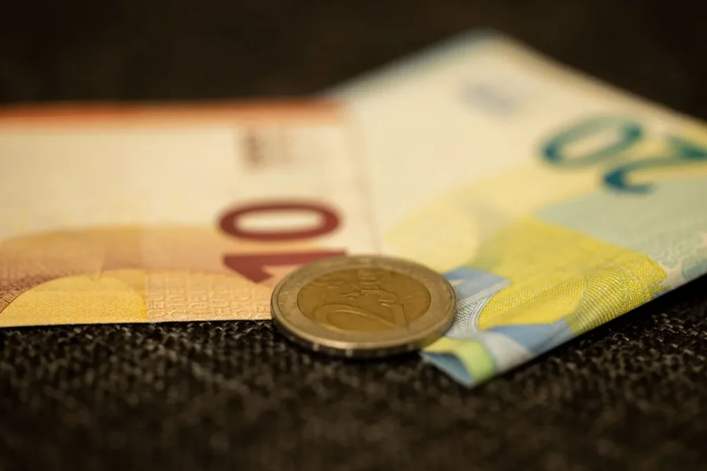 Euro-Geldscheine mit einer Zwei-Euro-Münze in Nahaufnahme auf dunklem Untergrund